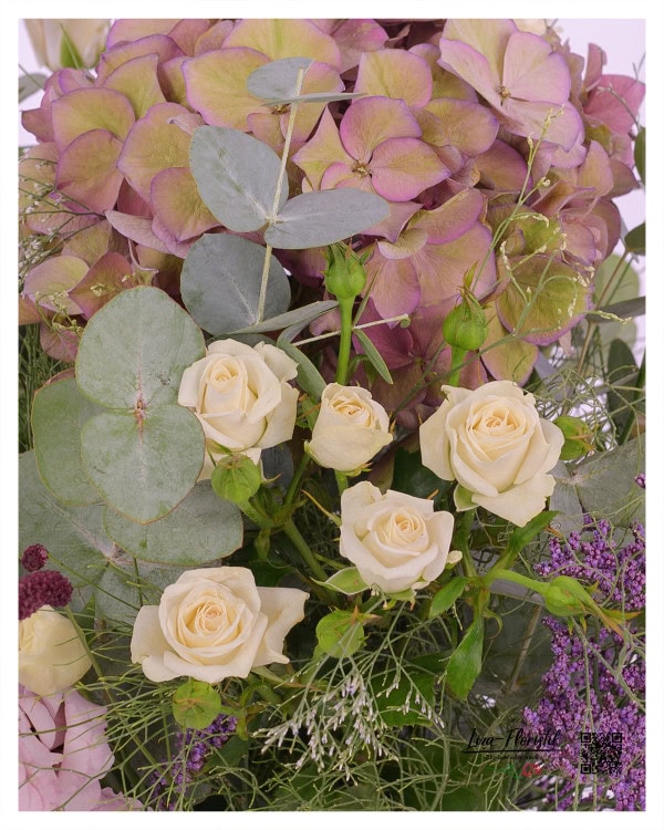 Die zart cremefarbenen Rosen setzen sich wunderschön von den weichen, pastellfarbenen Hortensien und dem Eukalyptusgrün ab und werden von feinem Strandflieder sanft umrahmt.