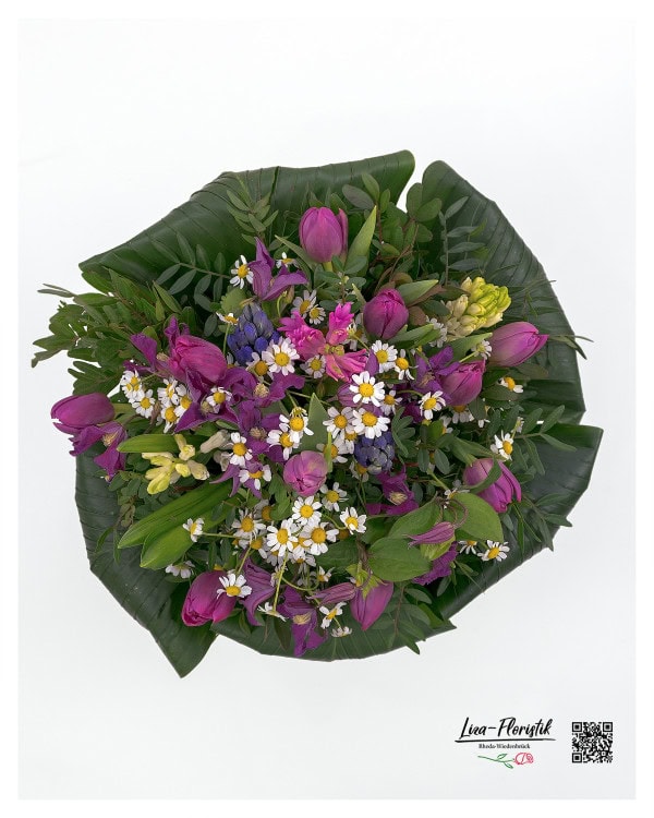 Der Frühlingsstrauß aus leuchtenden lila Tulpen, strahlend weißen Kamillenblüten, duftenden Hyazinthen, hellgelben Narzissen und zarten grünen Blättern präsentiert sich aus einer anderen Perspektive besonders harmonisch und lebendig.