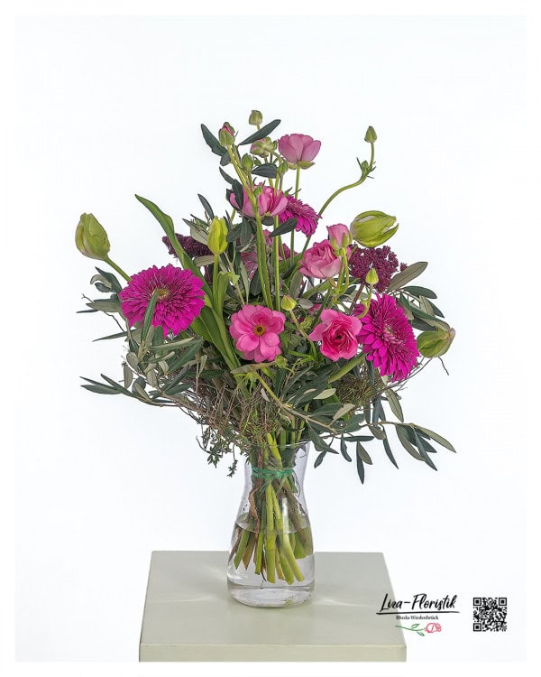 Blumenstrauß mit Schmetterlingsranunkeln, pinken Gerbera, Papageientulpen, Ammi, Spinosa und Olivenzweigen – luftig gebunden in natürlichen Grüntönen.