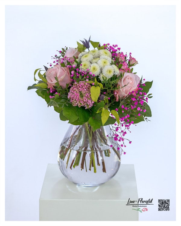 Blumenstrauß mit zartrosa Rosen, weißen Chrysanthemen, pinkem Schleierkraut, zarten Ranunkeln und frischem Grün, kunstvoll gebunden in einer harmonischen Farbkomposition.