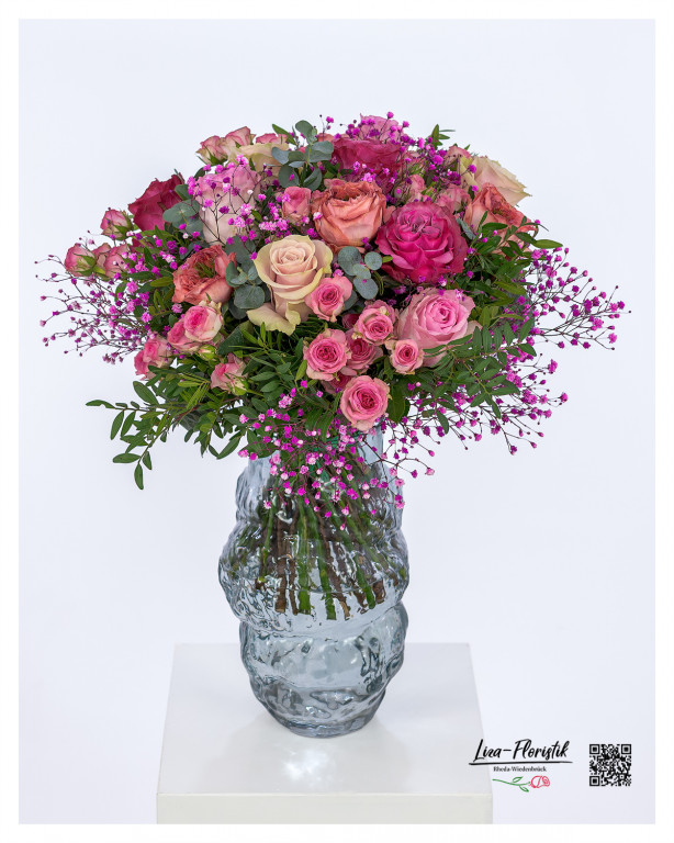 Üppiger, rund gebundener Blumenstrauß mit Rosen in verschiedenen Rosa- und Pinktönen, liebevoll kombiniert mit zartem, pinkfarbenem Schleierkraut, dezenten Eukalyptuszweigen und frischem Blattgrün.