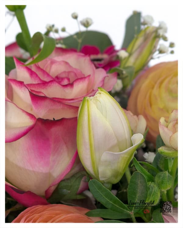 Frische Lilienknospe als Detail im Muttertag Blumenstrauß mit Rosen und Ranunkeln